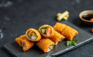 Temaki Frito dourado e crocante servido em prato com acompanhamentos típicos da culinária japonesa