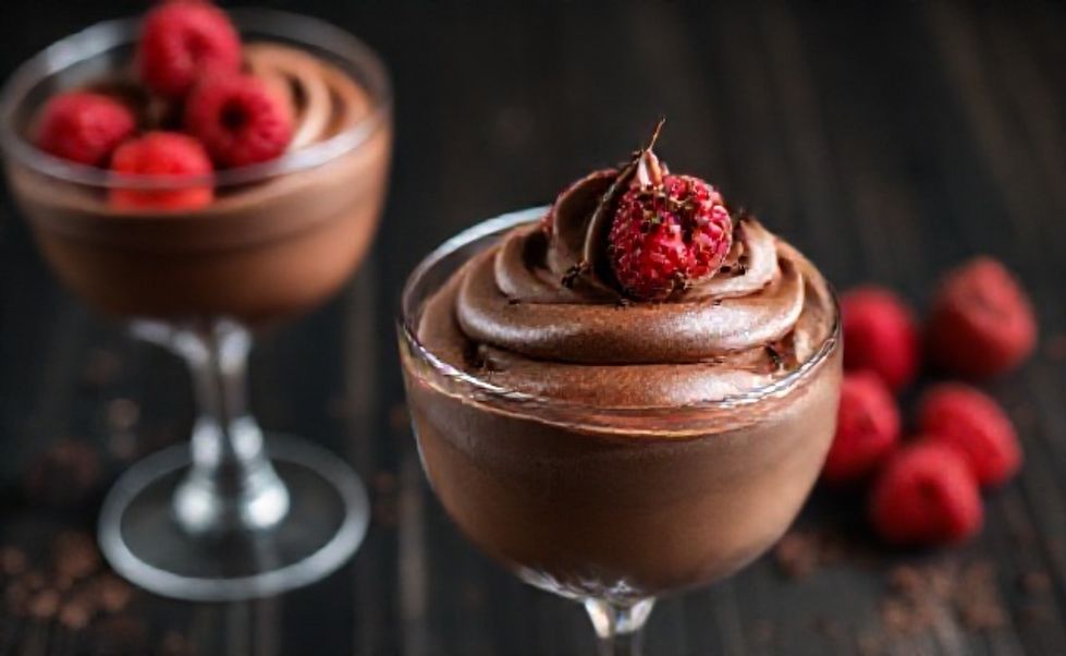 Mousse de Chocolate cremoso servido em taça de vidro, decorado com framboesas frescas e raspas de chocolate