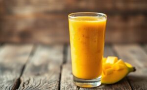 Smoothie receitas tropical cremoso em copo alto com decoracao de frutas, textura homogenea e cor vibrante laranja-amarela