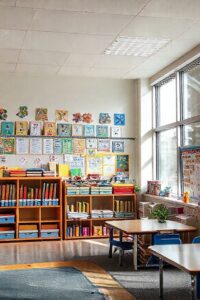 Sala de aula bem decorada com organizadores coloridos, painéis educativos e espaços definidos para diferentes atividades de aprendizado