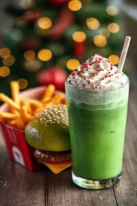 Grinch Meal McDonald's completa com hambúrguer verde, batatas fritas douradas e milkshake vibrante decorado com chantilly e confeitos vermelhos