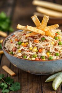 Salpicão de frango simples cremoso em bowl branco com batata palha crocante por cima, cenoura ralada laranja, milho amarelo e ervilhas verdes visíveis