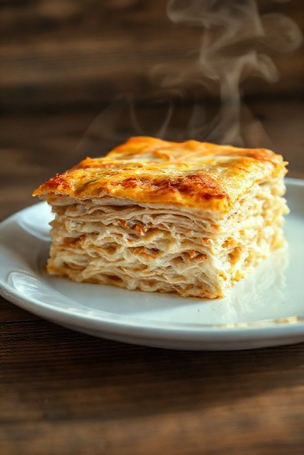 Fatia de lasanha ingredientes frango mostrando camadas de massa, frango desfiado, molho branco cremoso e queijo gratinado dourado