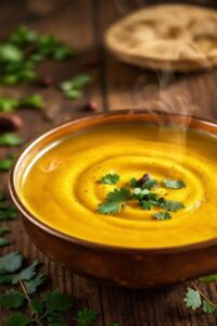 Cremoso molho roti ingredientes dourado servido em tigela de cobre com coentro fresco e especiarias, textura sedosa e aroma convidativo