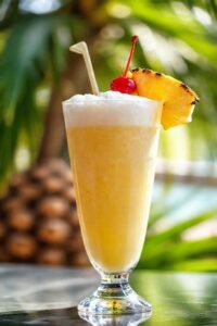 Pina colada cremosa servida em copo alto com fatia de abacaxi e cereja, mostrando os ingredientes para pina colada perfeitos