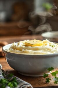 Purê de batata simples cremoso em tigela branca com manteiga derretendo, textura aveludada perfeita usando ingredientes selecionados