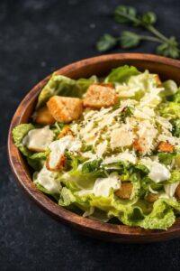 Salada Caesar Ingredientes finalizada em bowl com alface crocante, molho cremoso, croutons dourados e lascas de parmesão