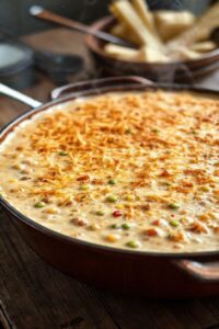 Prato de salpição de frango para 50 pessoas com cobertura dourada de queijo e batata palha crocante, servido em assadeira grande