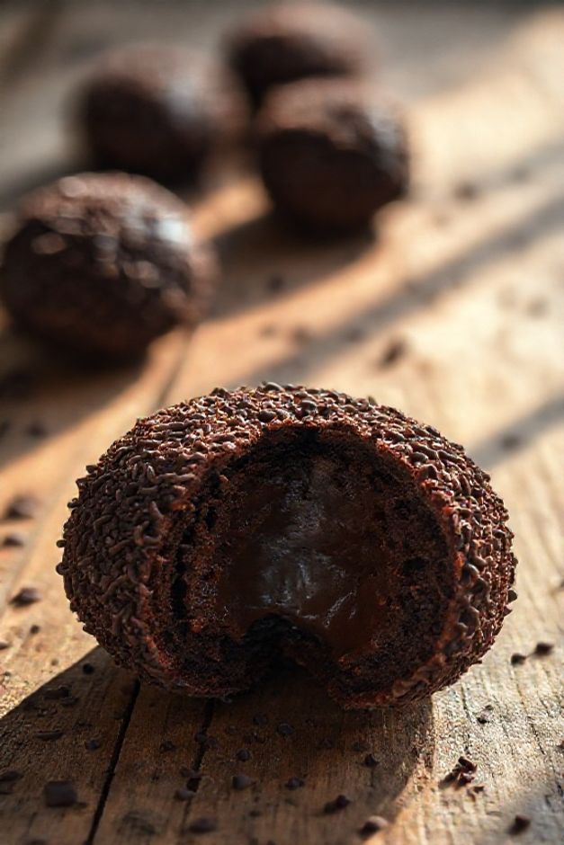 Brigadeiro brasileiro cortado ao meio mostrando seu interior cremoso de chocolate, coberto com granulado, demonstrando como fazer brigadeiro perfeito.