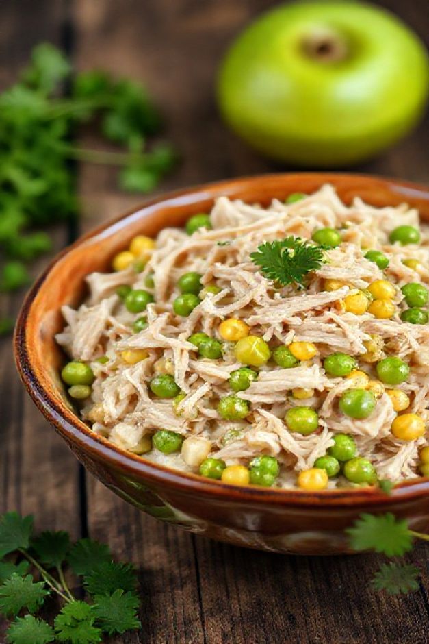 Salpicão simples ingredientes cremoso com frango desfiado, milho, ervilha e maçã verde em bowl cerâmico sobre mesa de madeira